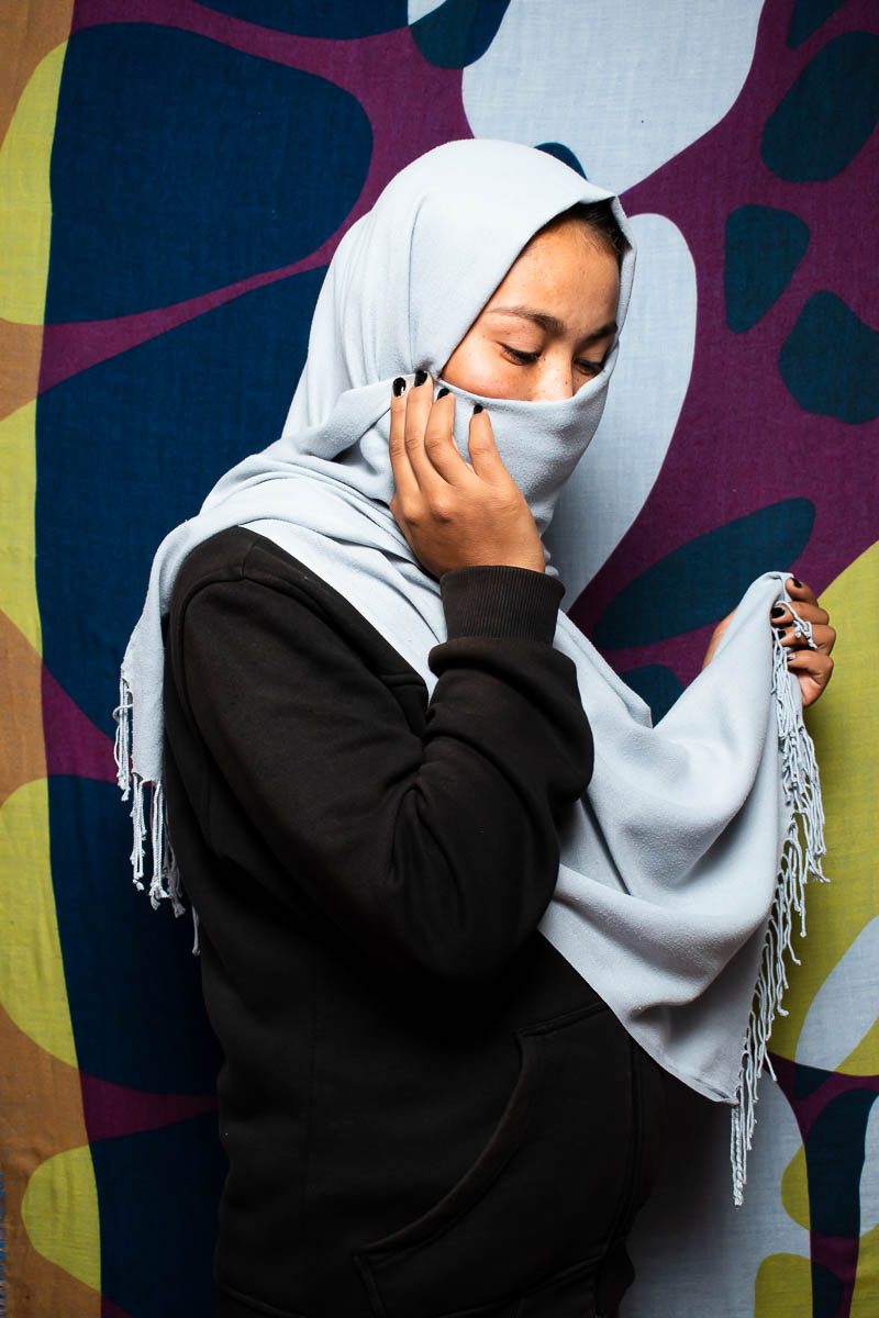 Portrait of refugee Sakine hiding her face with a gray hijab