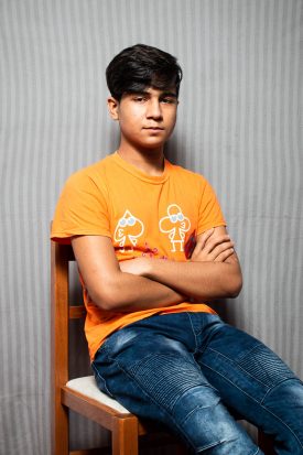 Portrait of refugee Ezatullah sitting on a chair with his hands crossed