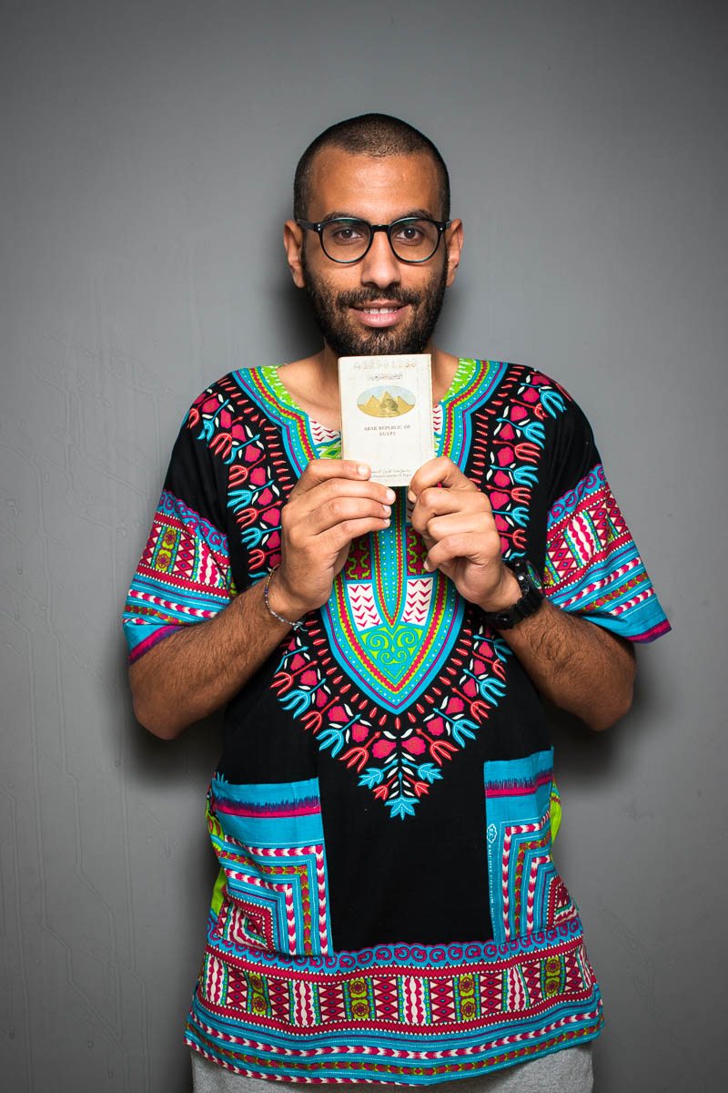 Portrait of refugee Omar holding a passport