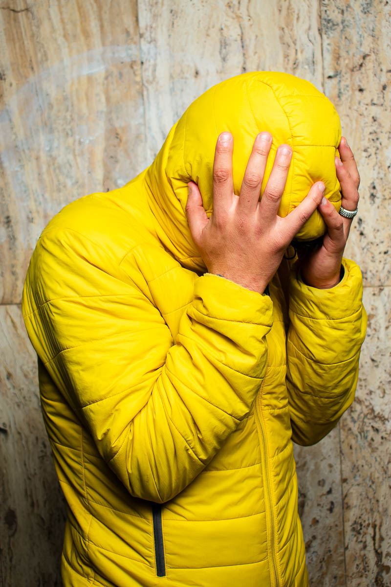 Portrait of Ismael who hides himself from the camera wearing a yellow jacket