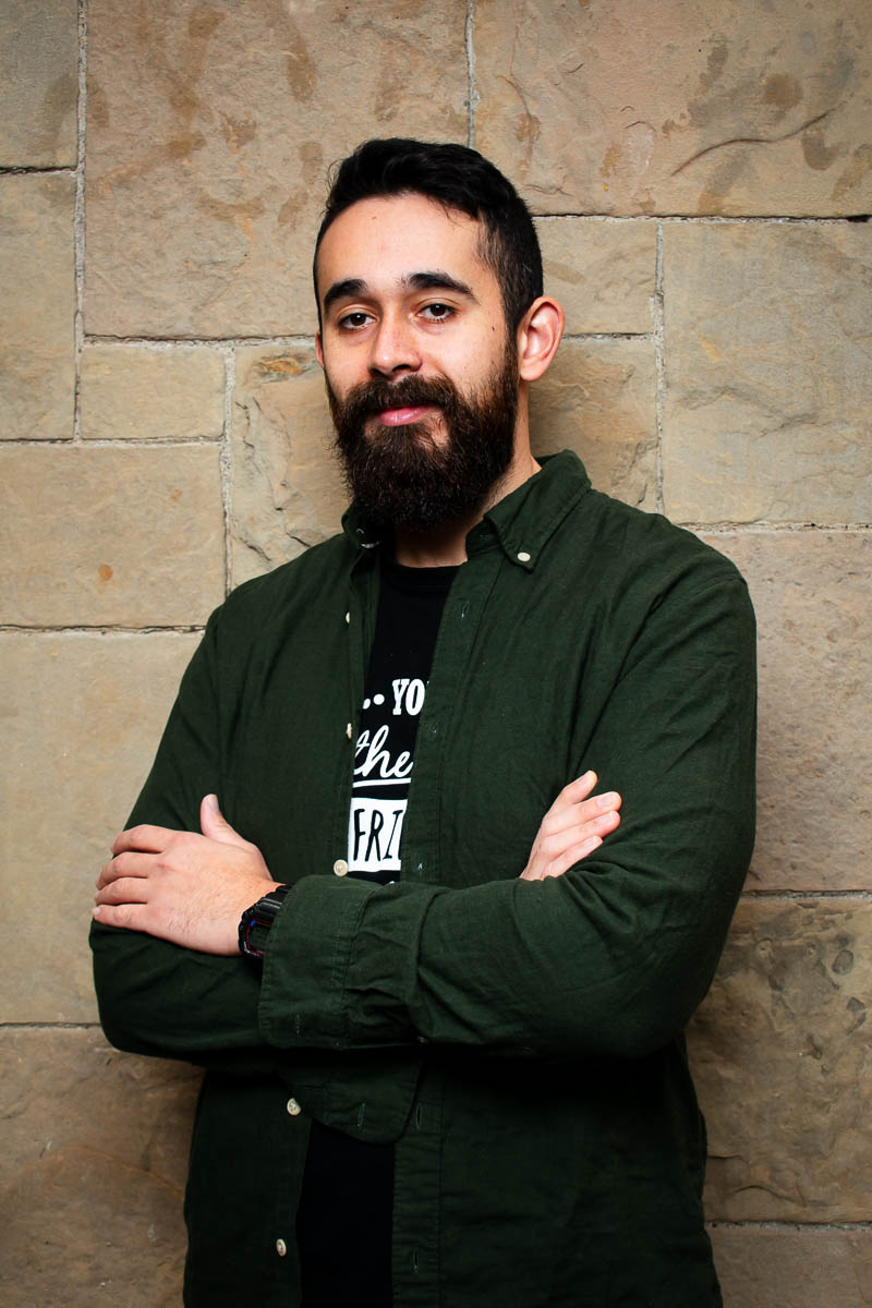 Portrait of refugee Oussama smiling with his arms folded across