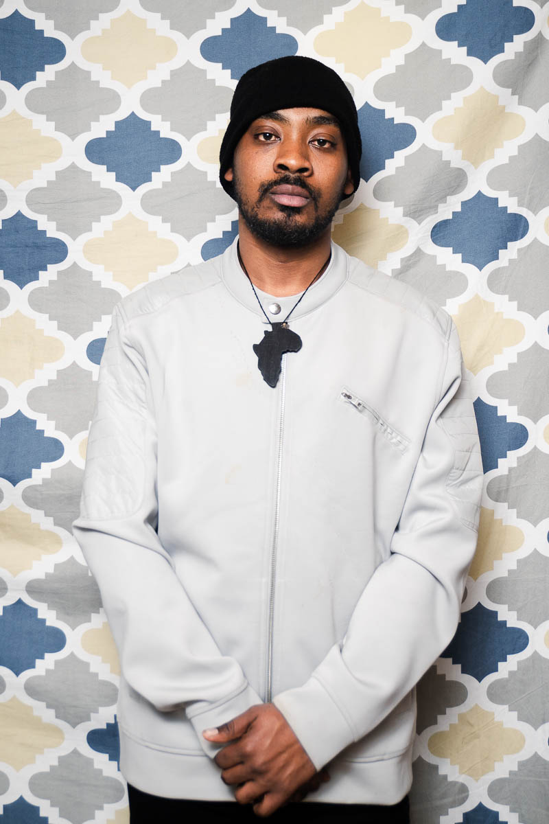 Portrait of Adonis, facing the camera in a neutral way wearing a white polo.