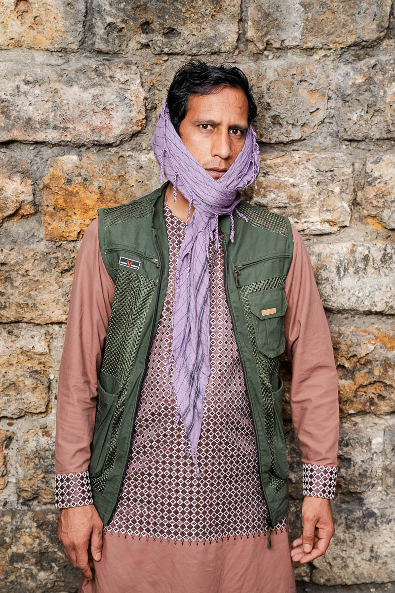 Portrait of Hzareah, looking at the camera while putting a cloth on his face wearing a green blazer