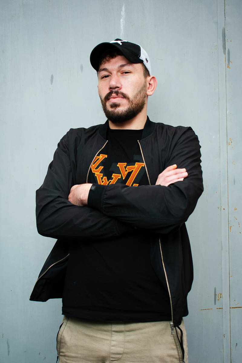 Portrait of Mohammed, facing the camera both arms are wrapped in stomach and wearing a black jacket.