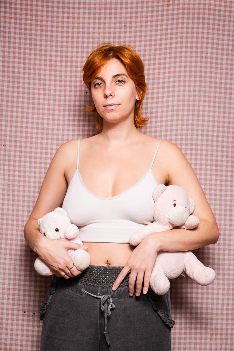 Portraif or Razan, facing the camera holding stuff toys in each hands and is wearing a white sleeveless.