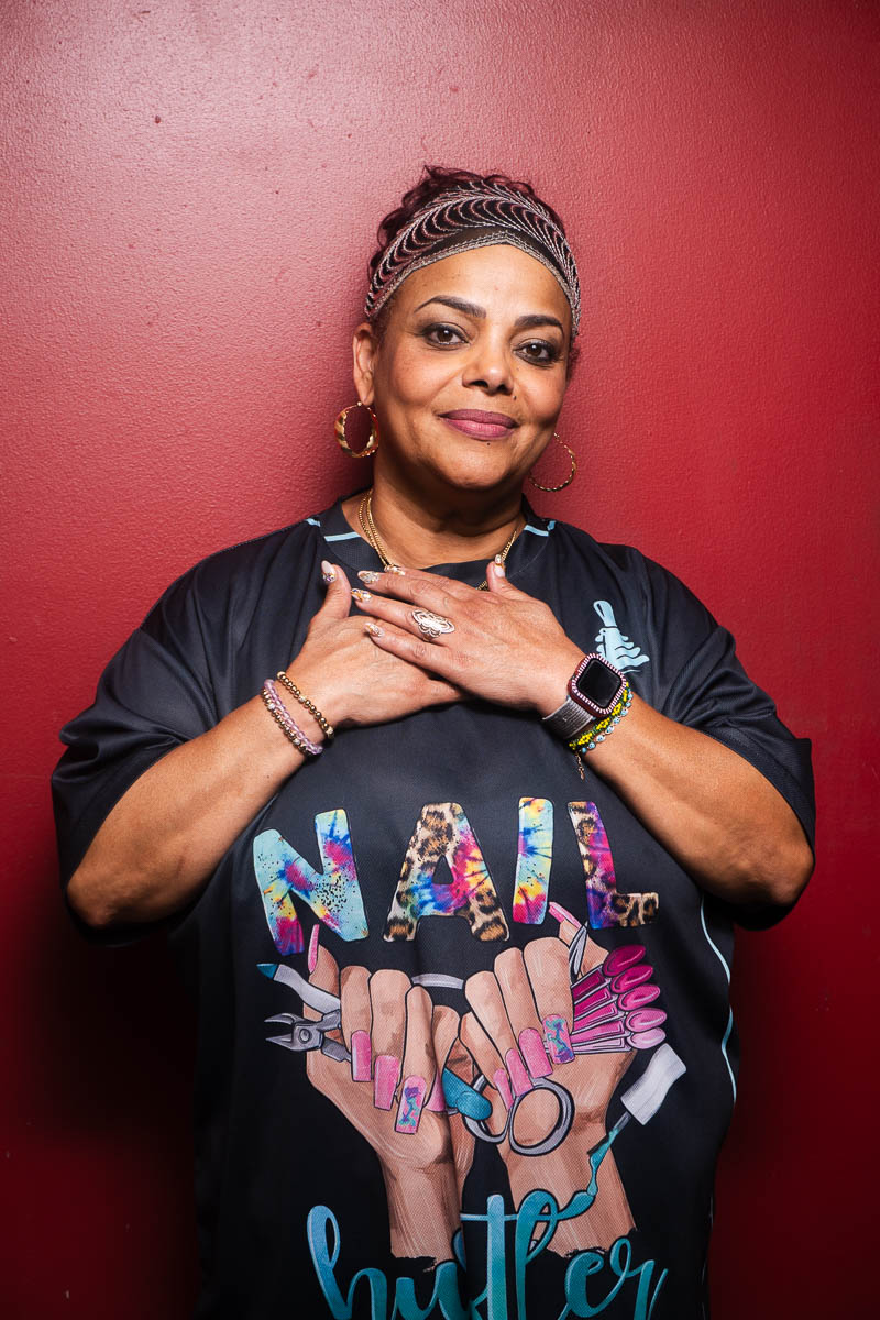 Portrait of Aly, smiling in in the camera, hands clasped in chest.
