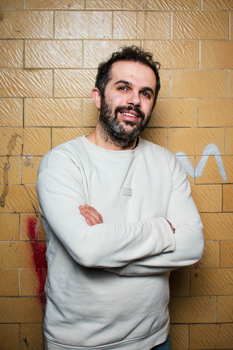 Portrait of Adnan, smiling in the camera wearing a white jacket.