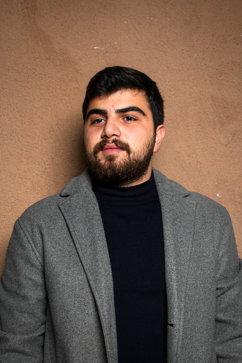 Portrait of Ahmad, wearing a suit and black shirt underneath.