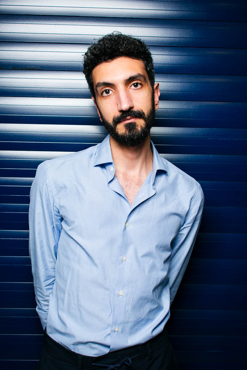 Portrait of Shams, hands at the back, facing neutral in the camera and is wearing a blue polo long sleeves.