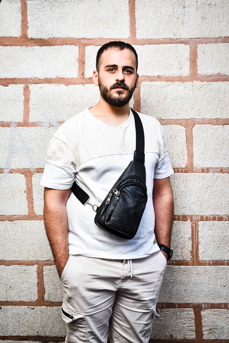 Portrait of Wael, facing neutral in the camera, both hands in purse, and is wearing a white shirt and pants.