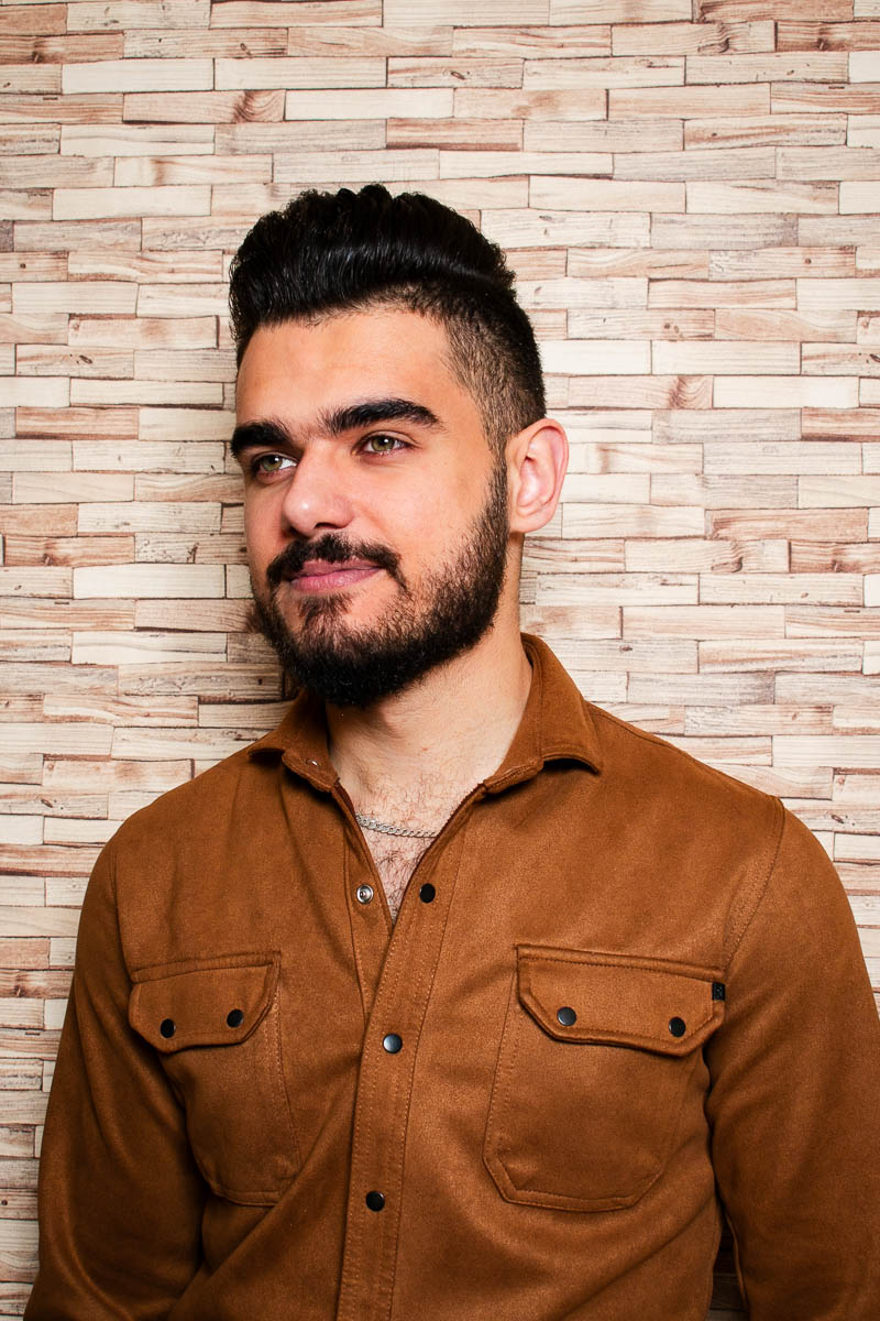 Portrait of Adnan, facing sideward from the camera and is wearing a brown denim jacket.