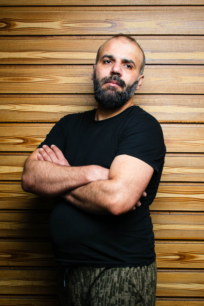 Portrait of Hasan, positioned sideward and is facing neutral in the camera, arms crossed and is wearing a black shirt.