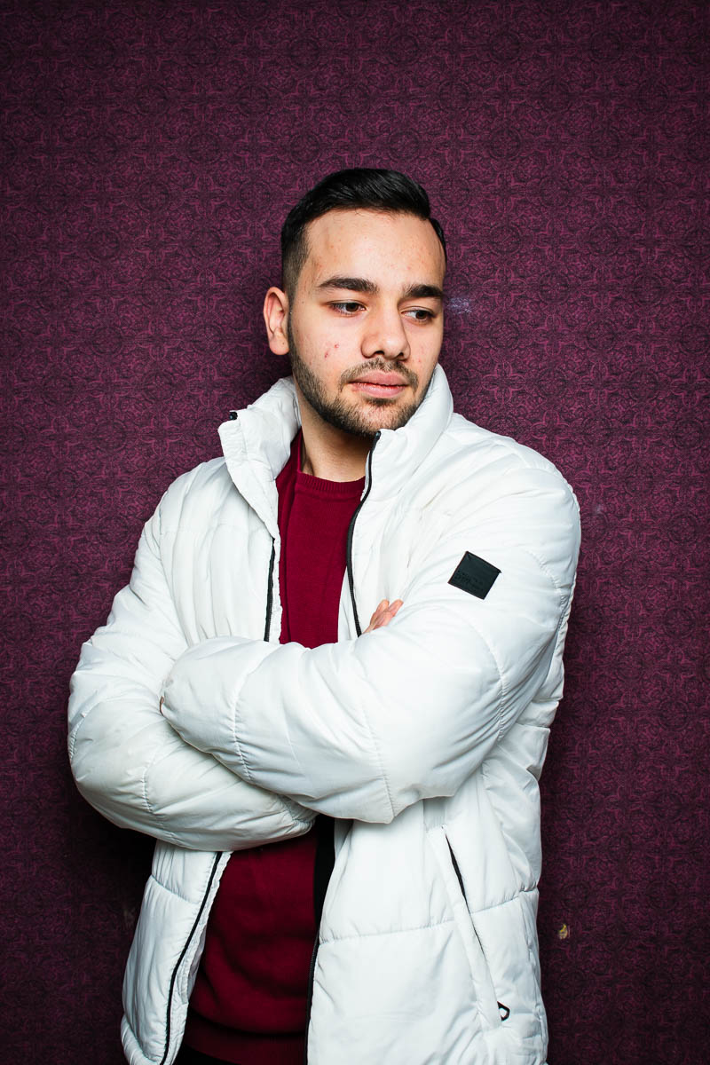 Portrait of Mahmod, clasping arms together and is wearing a white hoodie jacket.