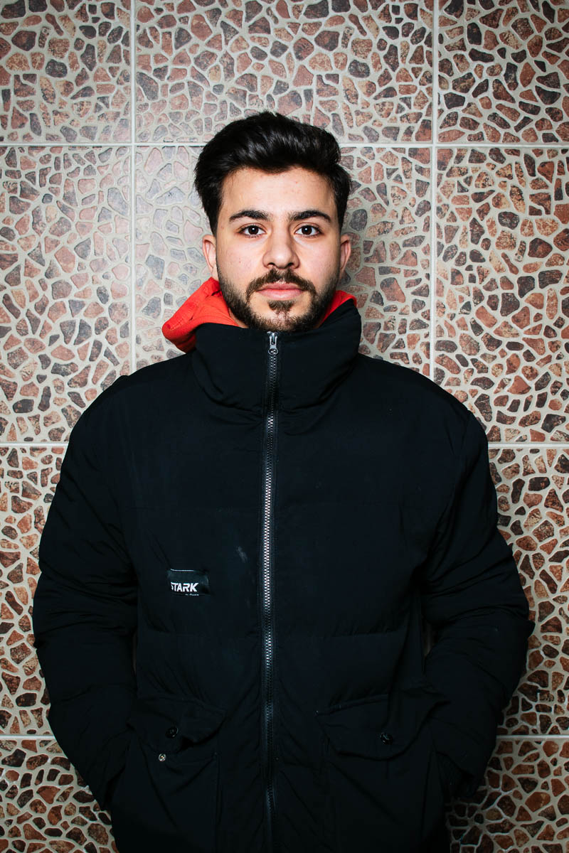 Portrait of Mohamad, staring neutral in the camera wearing a black hoodie jacket.