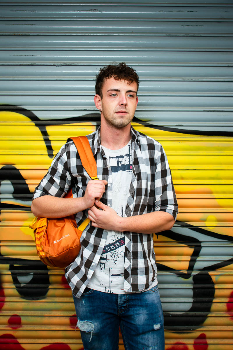 Portrait of Andrei, not facing directly to the camera wearing a striped polo and carrying an orange bag.