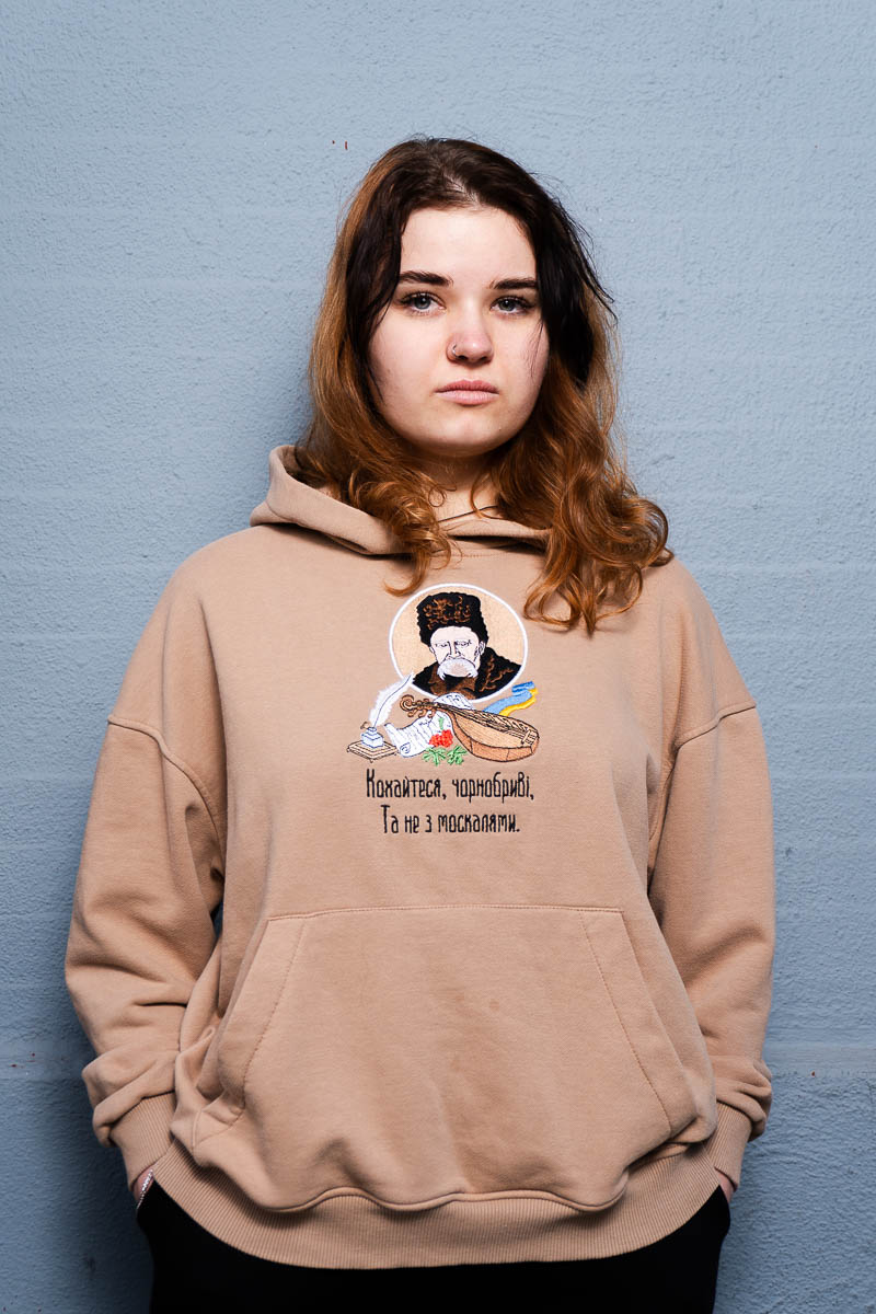 Portrait of Lesia looking intently at he camera and is wearing a brown jacket.