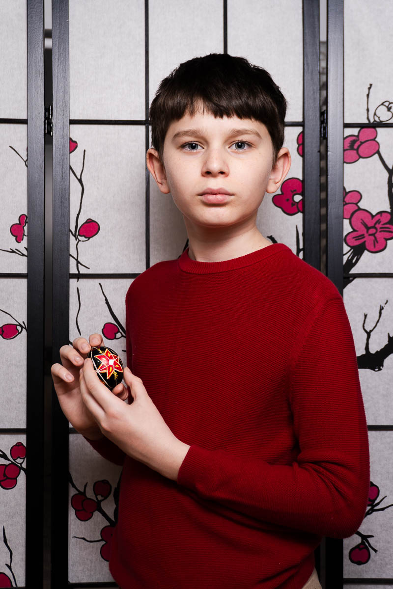 Portrait of Arthur, looking intently at the camera and is wearing a red long sleeves.