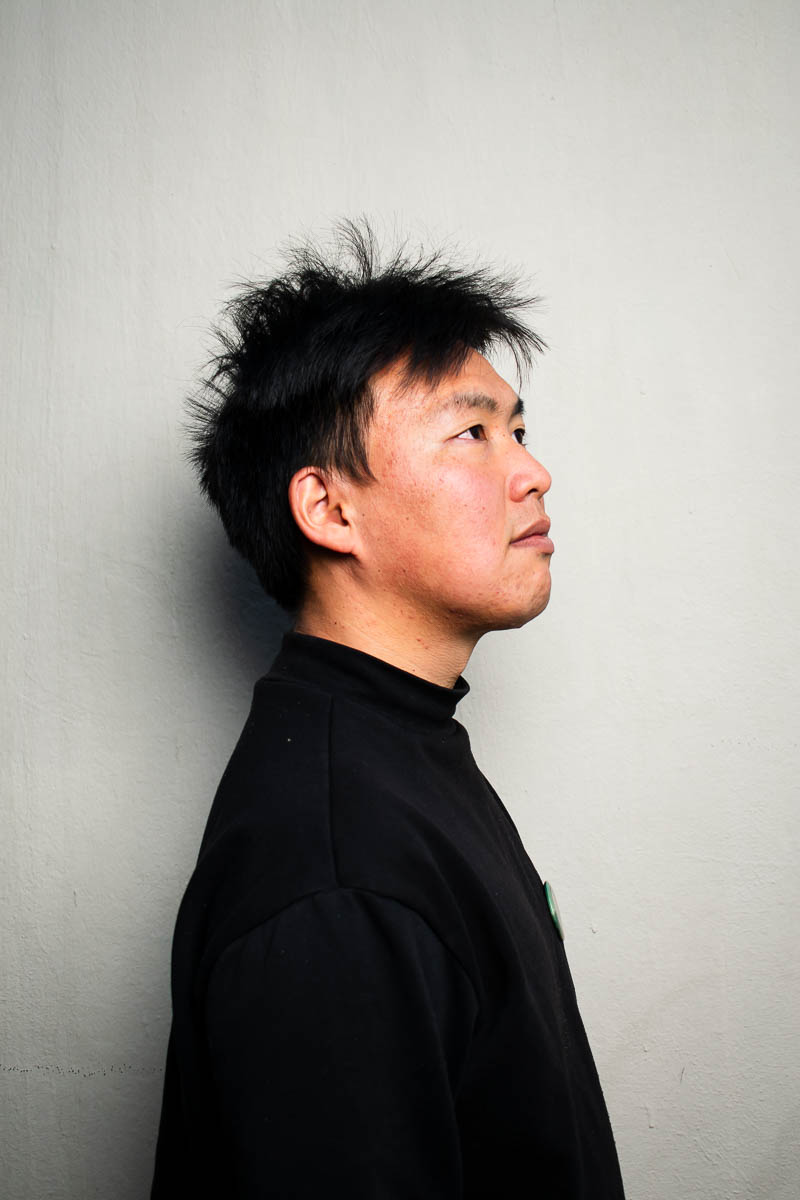 Portrait of Xinquin, facing sideward and is wearing a black shirt.