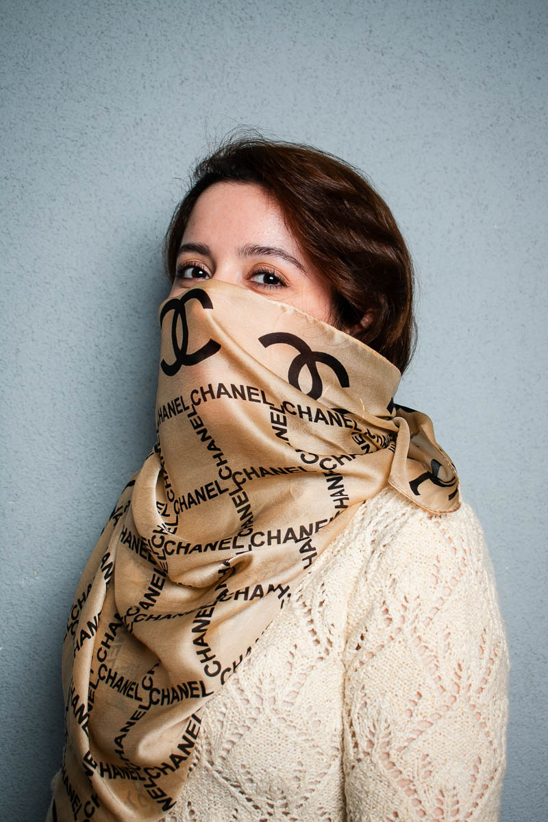 Portrait of Sara, covered her nose and mouth with a chanel cloth and is looking at the camera.