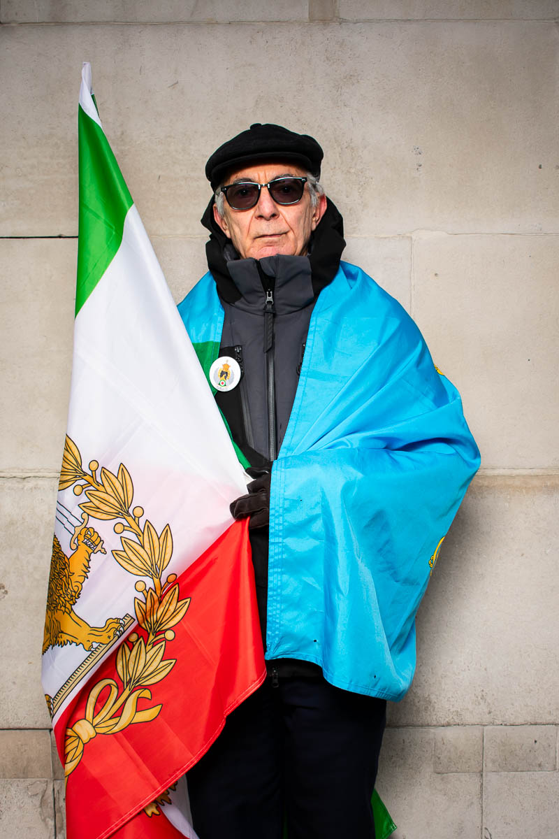 Portrait of Mohammad, holding a flag wearing shades facing the camera.