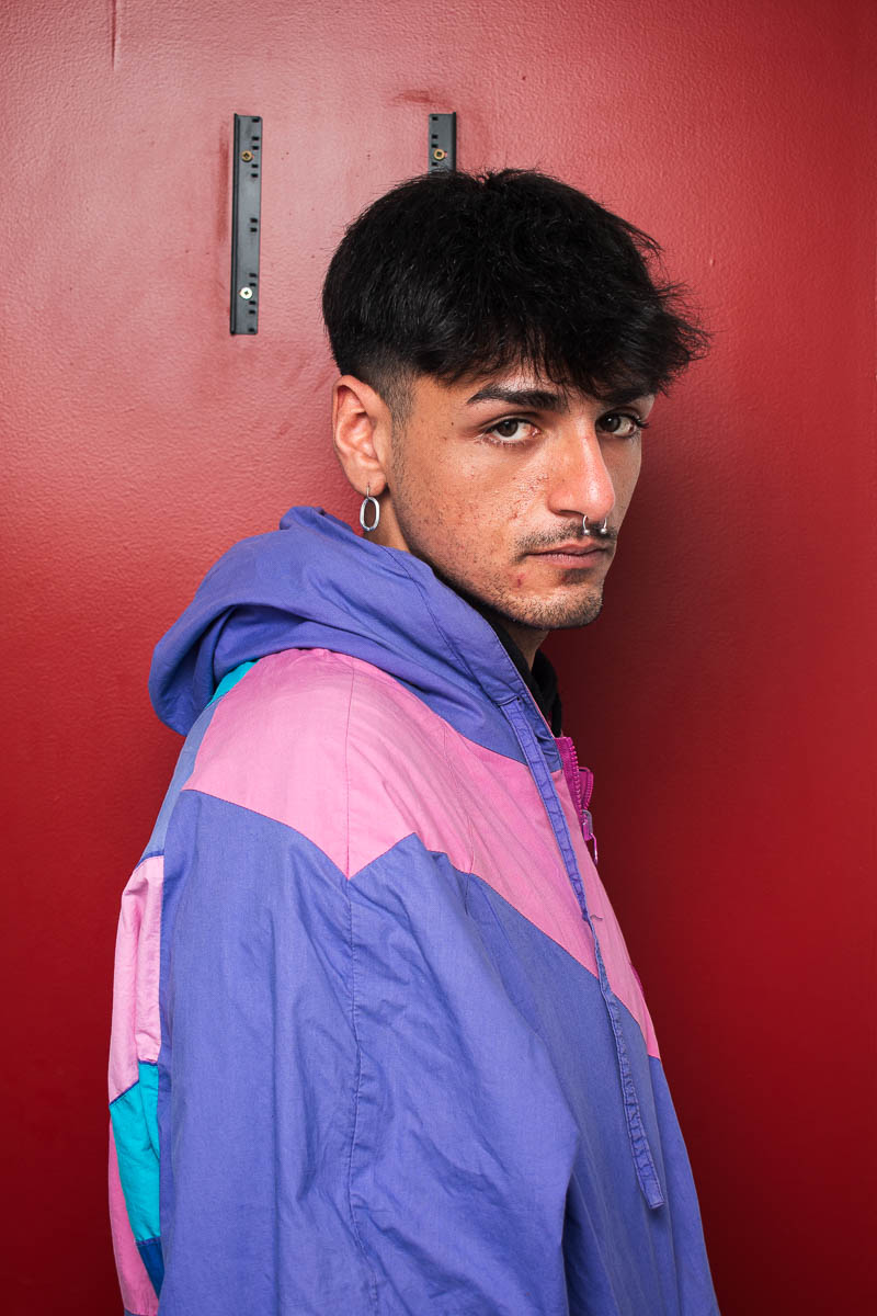 Portrait of Ivan, looking intently at the camera and is wearing a purple and pink jacket.