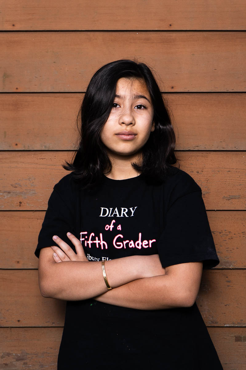 Portrait of Raihana, facing the camera intently, arms crossed and is wearing a black shirt.