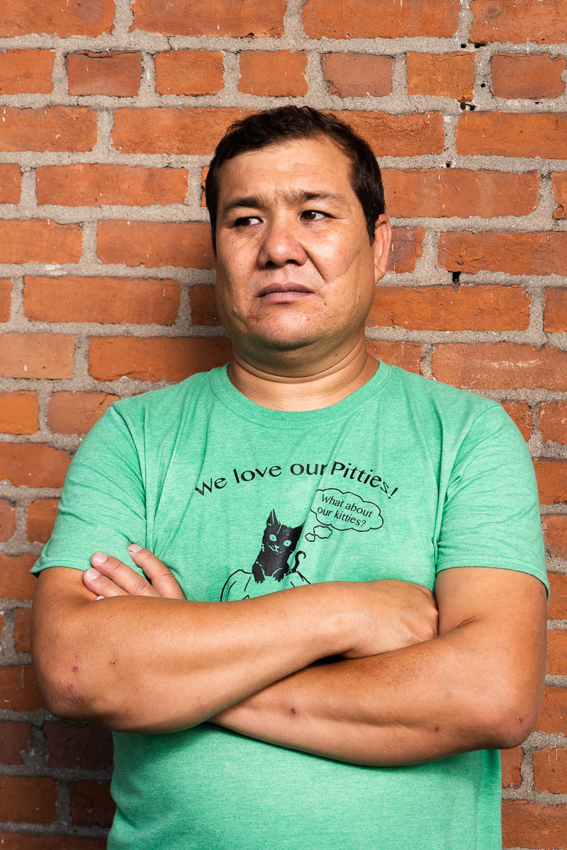 Portrait of Azim, arms crossed and is wearing a light green shirt.