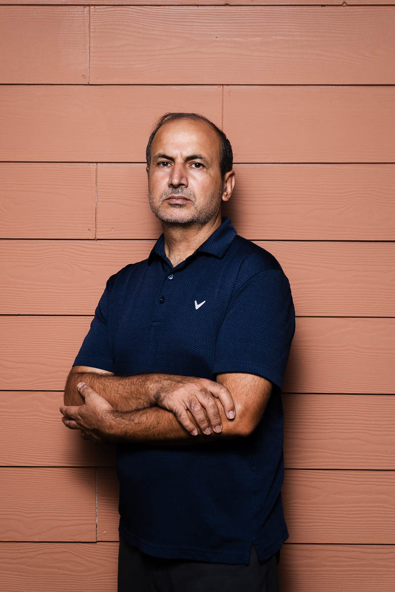 Portrait of Khan, arms crossed together, and is wearing a dark blue polo shirt.