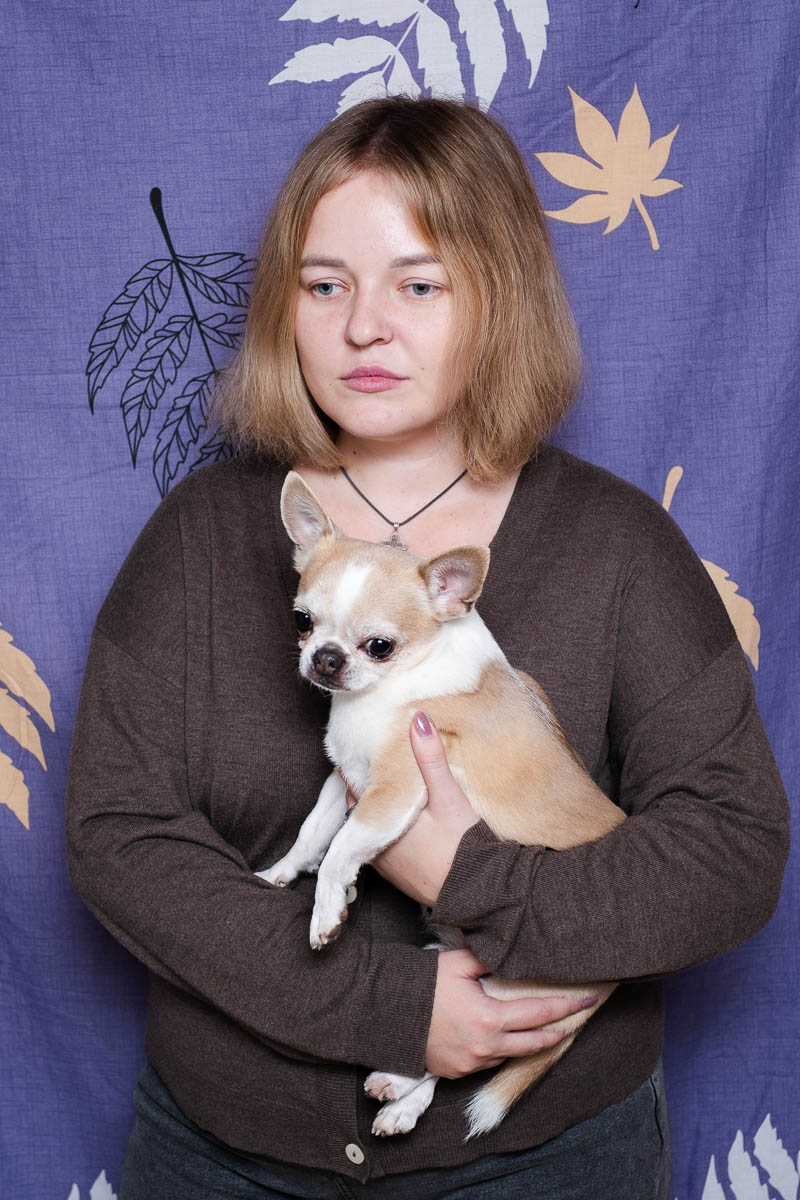 Portrait of Cristina, not looking directly in the camera and is holding a puppy.