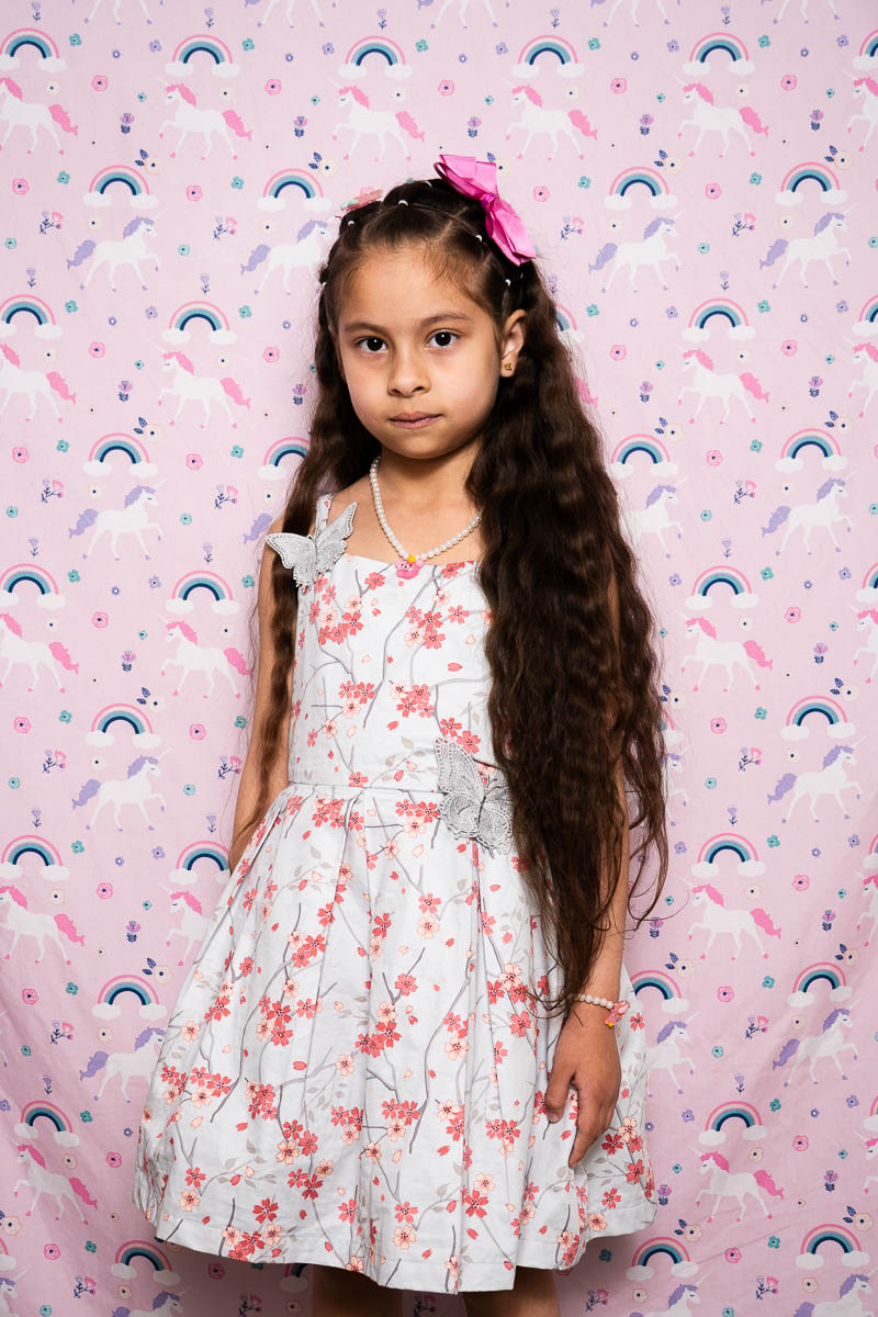 Portrait of MS, a young girl wearing a floral dress and a pink ribbon clip.