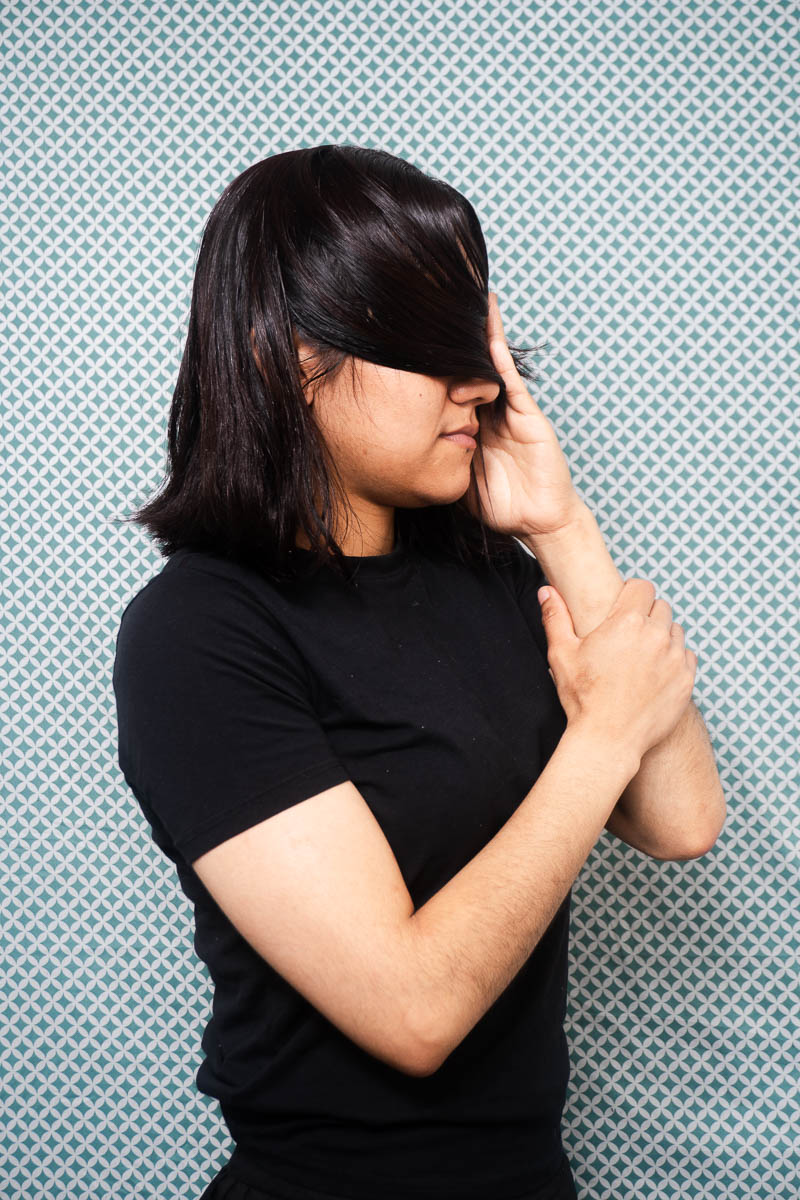 Portrait of Katerin, hiding her face using her hair and is wearing a black shirt.