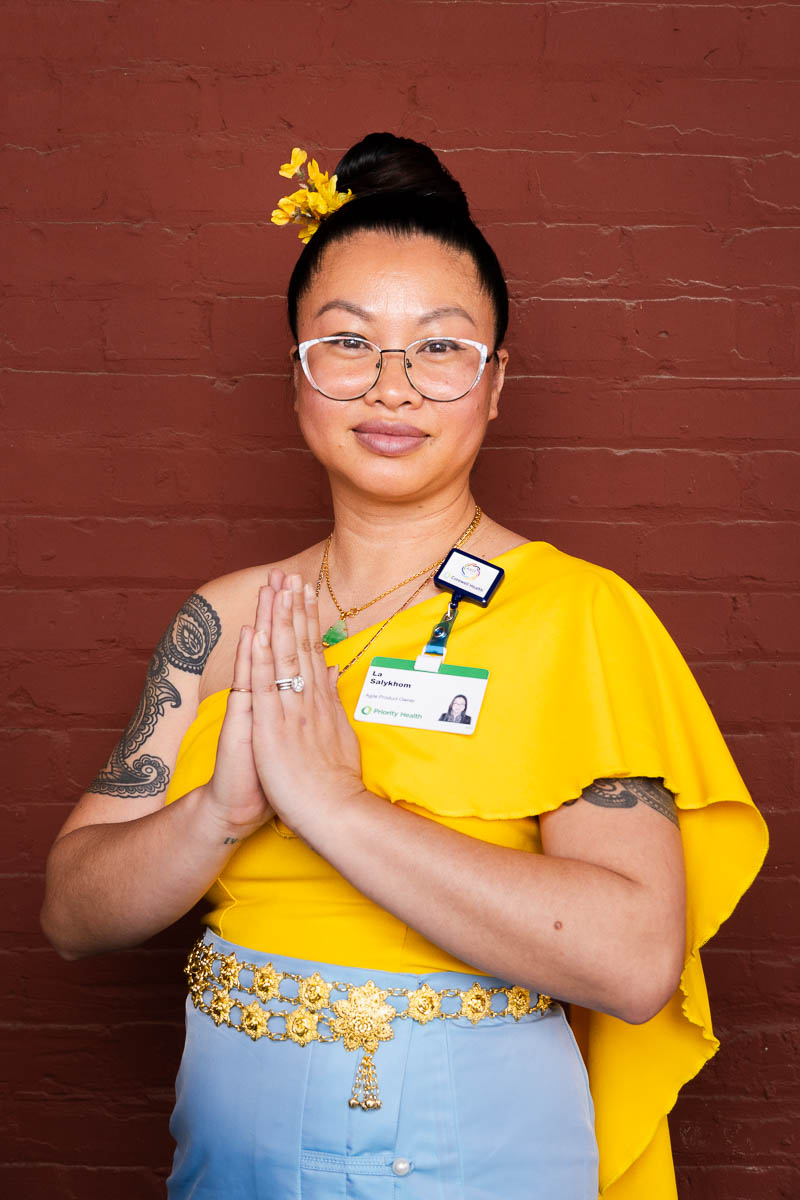 Portrait of La, smiling in the camera and is wearing a yellow top and a hairdress with eyeglasses.