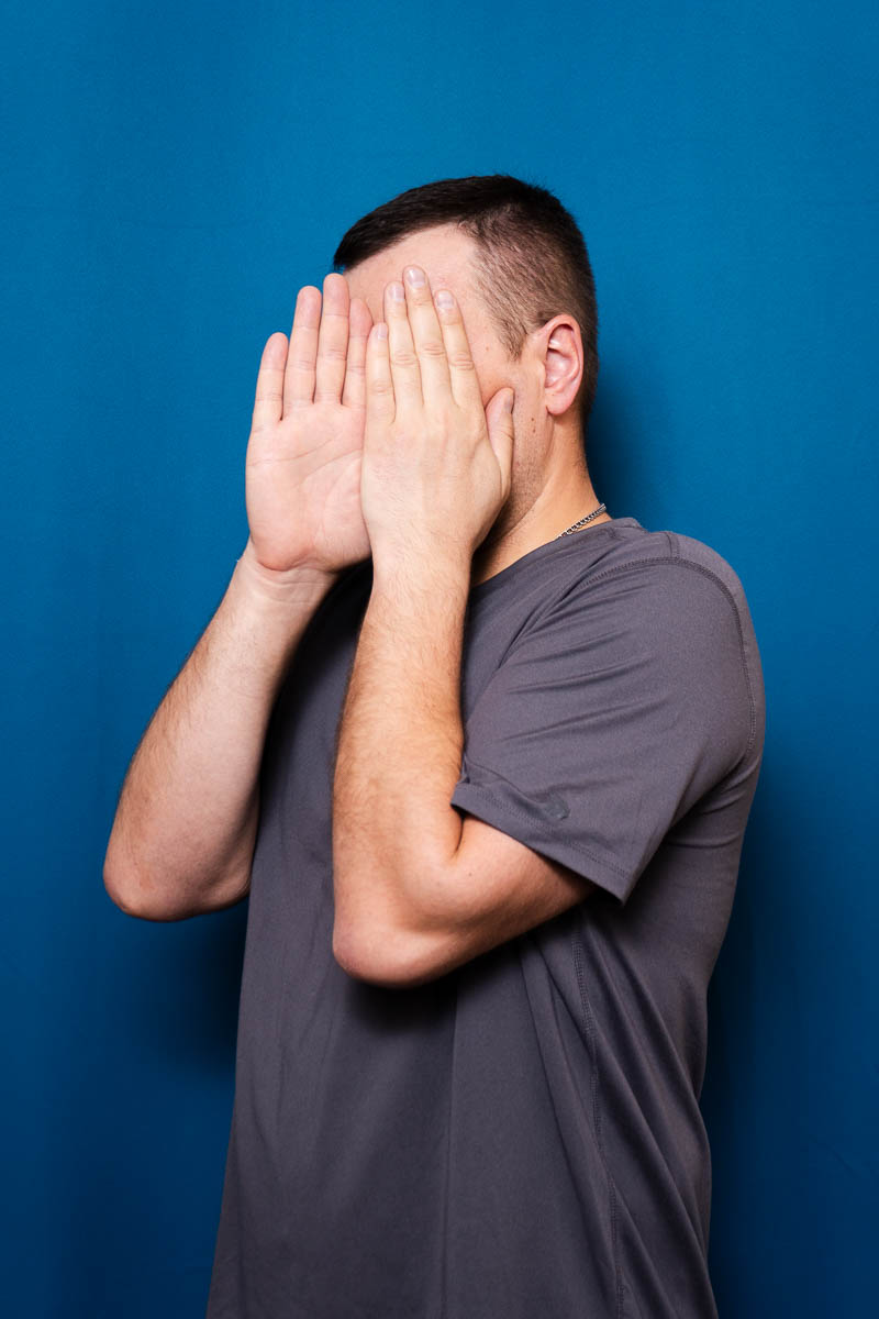 Portrait of Yaroslav, hiding his face in the camera using his hands.