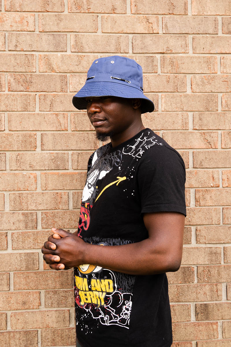 Portrait of Gael facing sideward and is wearing a purple hat and black printed shirt.