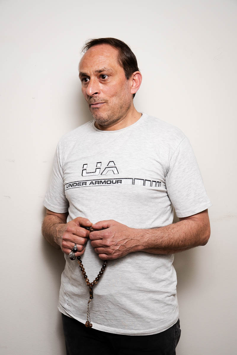 Portrait of Hma, wearing a white t-shirt and is holding a rosary.