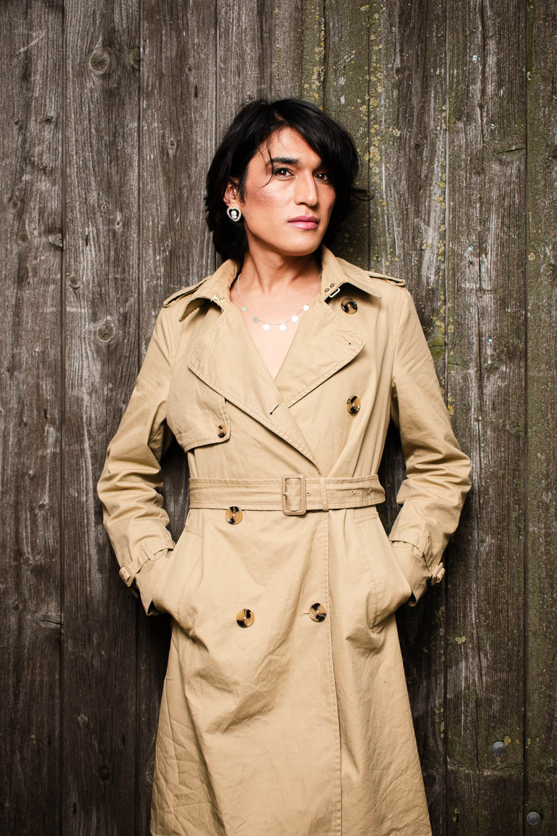 Portrait of Diba, looking at the camera wearing a beige dress - hands in purse.