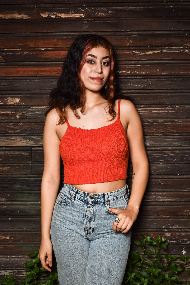 Portrait of Miran, smiling in the camera and is wearing a red sleeveless and pants.