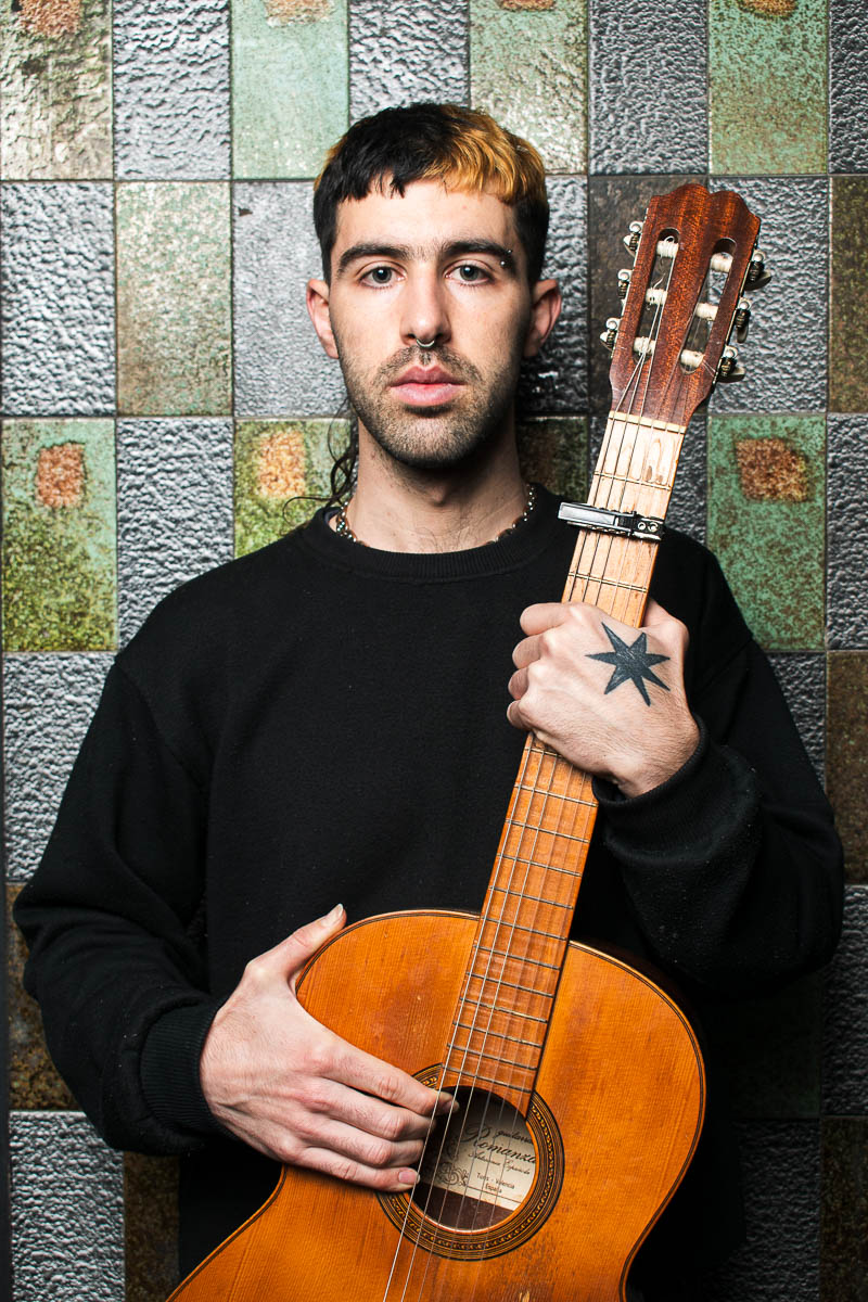 Portrait of Lucas, facing the camera with a guitar in hand.